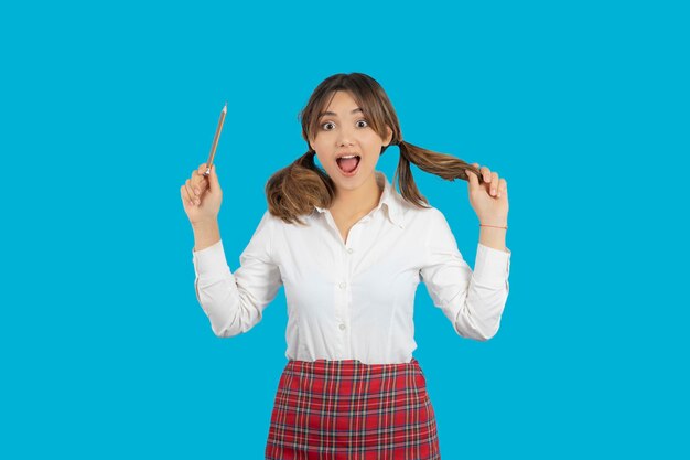 Shocked young college girl holding pen and straighten her hair. High quality photo