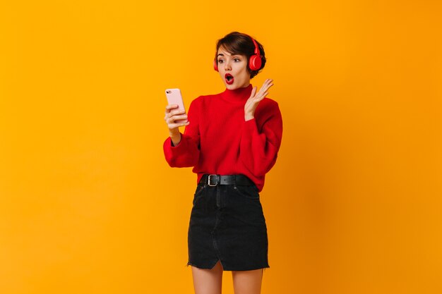 Shocked young lady in black skirt looking at smartphone