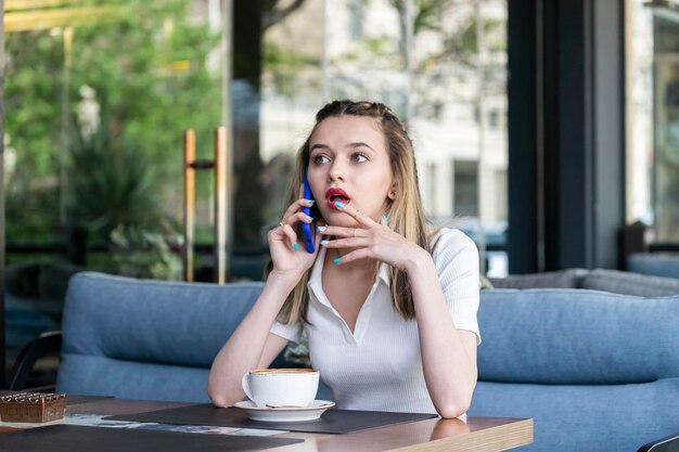 Shocked young lady talking on the phone at the restaurant