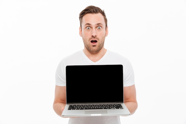 Shocked young man showing display of laptop.