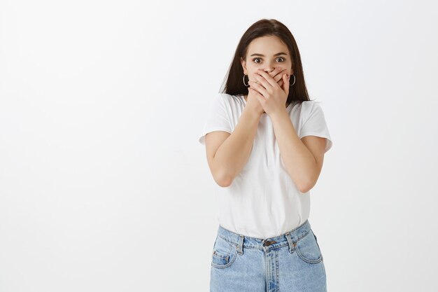 shocked young woman posing against white wall