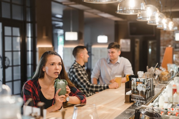 Free photo shocked young woman sitting near the bar counter holding drinks