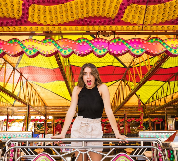 Free photo shocked young woman standing at amusement park