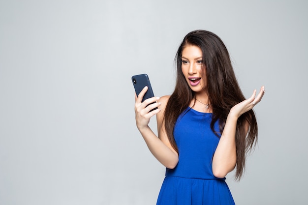 Shocking news. Business and technology. Close up portrait of surprised young woman using smart phone isolated