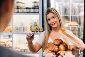 Free photo shop assistant preparing croissant bag