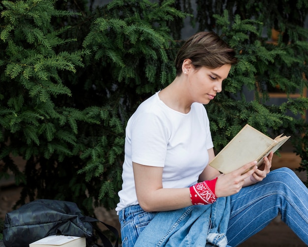 Short-haired female sitting with book in park