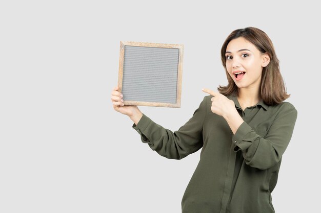 Shot of adorable young woman showing empty frame over white. High quality photo