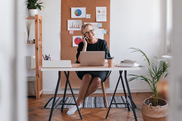 Free photo shot of business woman in black dress talking on phone