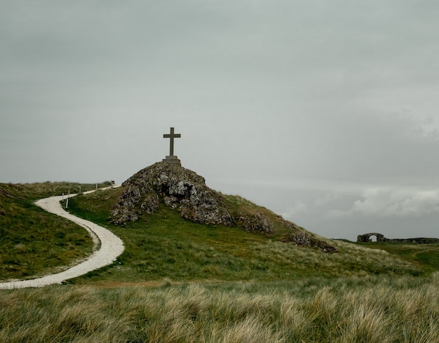 Free photo shot of a cross placed on a pedestal placed on a rocky hill