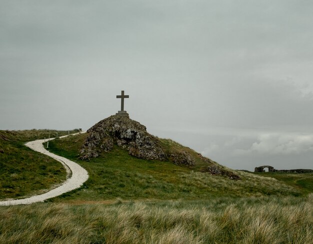 Shot of a cross placed on a pedestal placed on a rocky hill