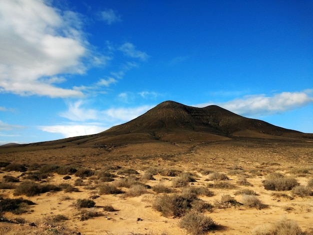 Free photo shot of a dry wasteland and a mountain in the distance in corralejo natural park, spain