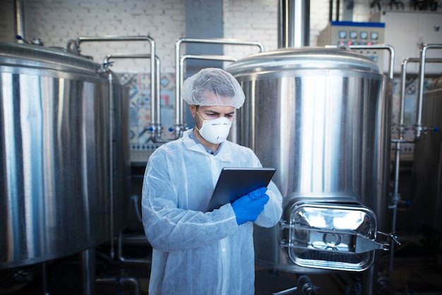 Free photo shot of highly concentrated and focused caucasian technologist controlling production in food processing factory or pharmaceutical industry