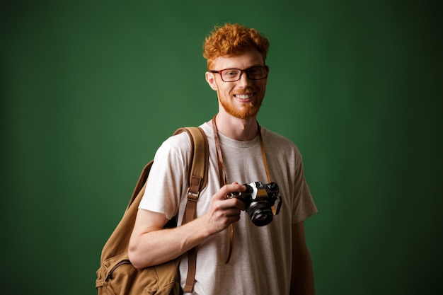 Free photo shot of readhead bearded hipster with retro camera and backpack