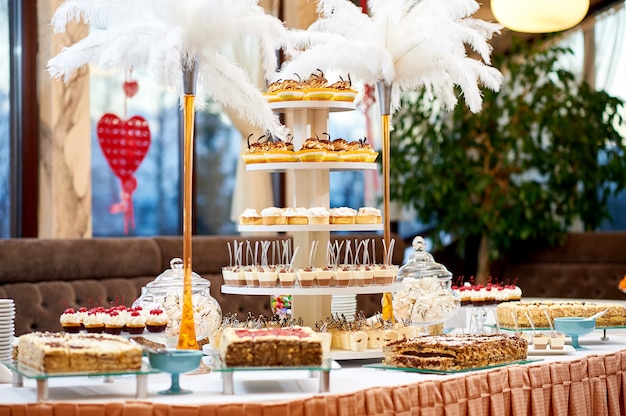 Free photo shot of a restaurant table with plenty of different tasty desserts cupcakes and creamy cakes sweet sugar eating cafe celebration concept.