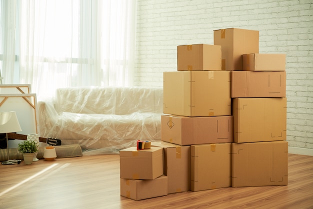 Free Photo shot of room interior with package boxes standing in the middle and sofa covered with film