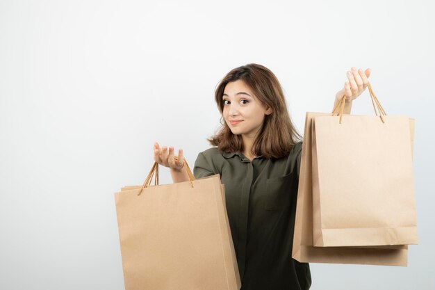 Shot of young female model with craft bags standing over white. High quality photo