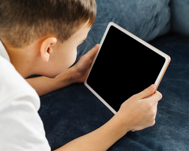 Over the shoulder view child holding digital tablet