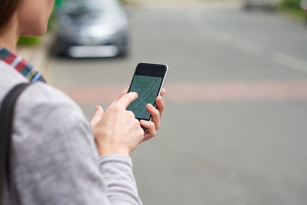 Free Photo over the shoulder view of unrecognizable person tracking taxi on the mobile app