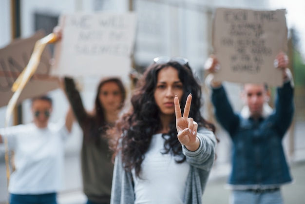 Free photo showing gesture by two fingers. group of feminist women have protest for their rights outdoors