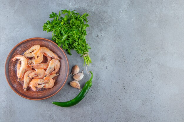 Shrimps on a plate next to parsley bunch , on the marble background. 