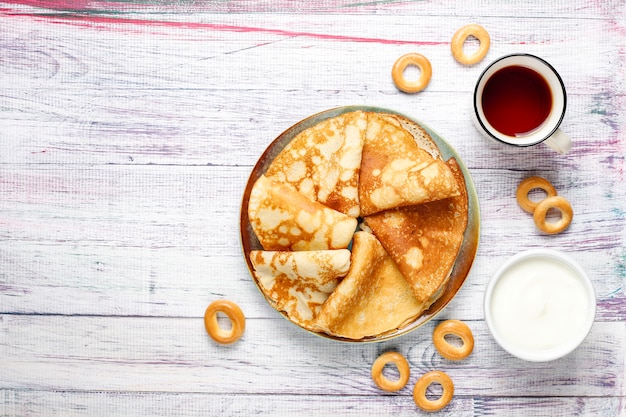 Shrovetide Maslenitsa festival meal. Russian pancake blini with raspberry jam, honey, fresh cream and red caviar,sugar cubes,cottage cheese,bubliks on light background