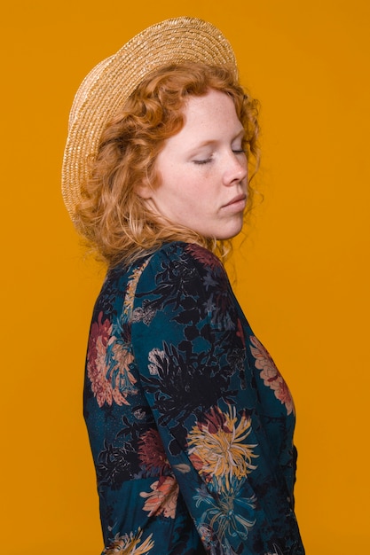 Free photo shy curly redheaded female in studio with bright background