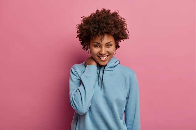 Free Photo shy romantic curly woman smiles happily, touches neck