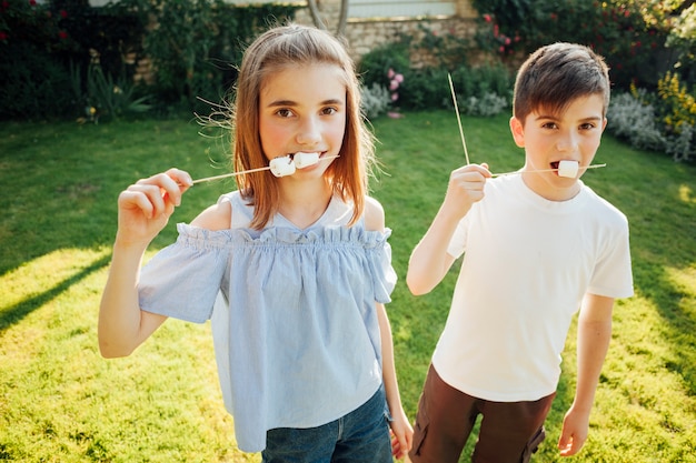 Free photo sibling eating marshmallow and looking at camera