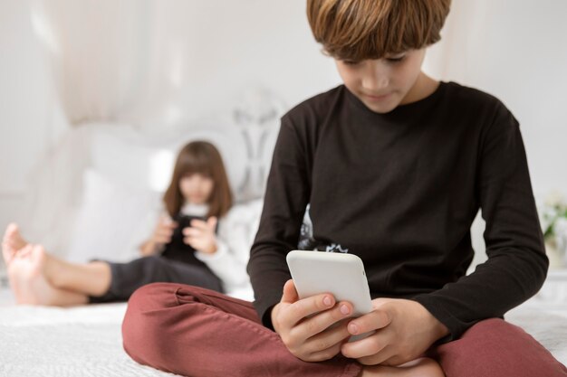 Siblings in bedroom with phone