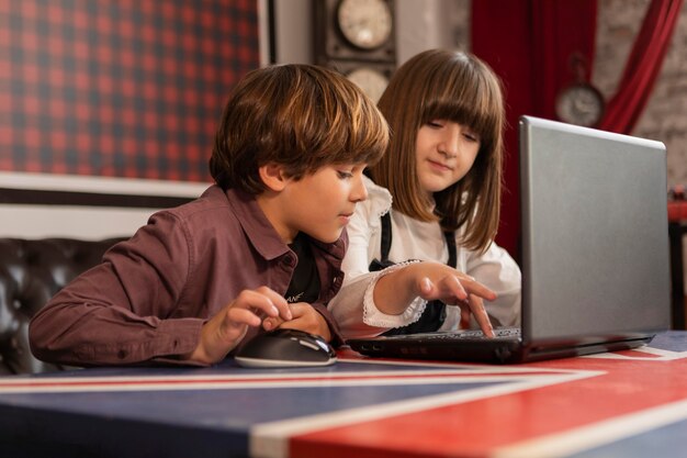 Siblings at home using laptop