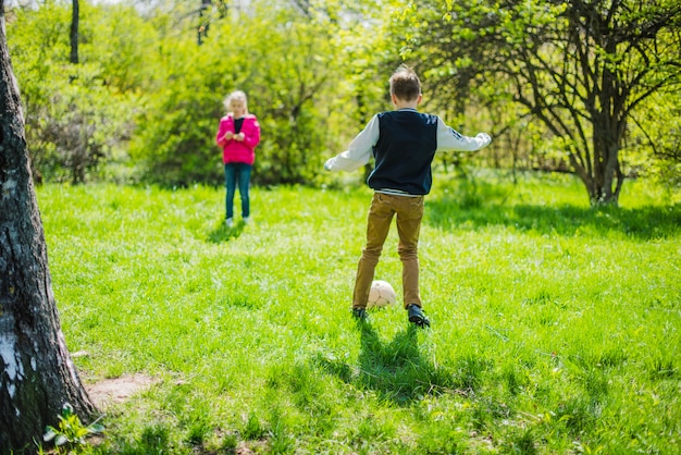 Siblings playing soccer outdoors