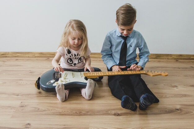 Free photo siblings playing with a guitar