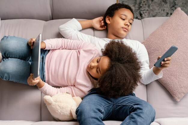 Siblings using tablet and mobile at home