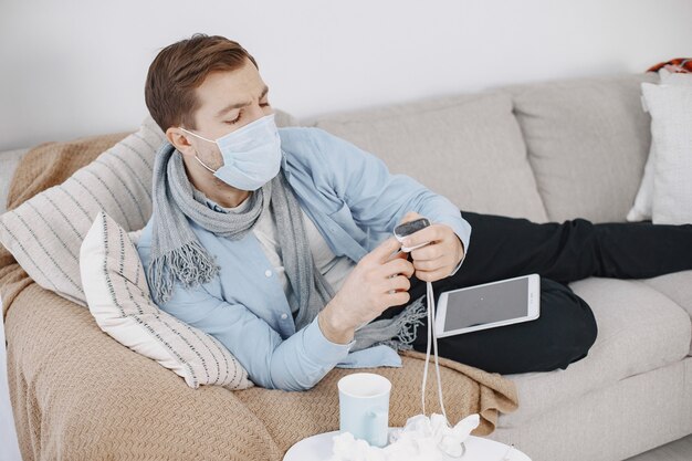 Free Photo sick guy in living room. middle age man feeling sick with cold and fever at home. man in a medical mask.