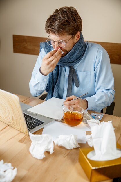 Sick man while working in office, businessman caught cold, seasonal flu.