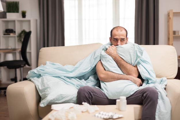 Sick man with chills wrapped in blacket during quarantine.