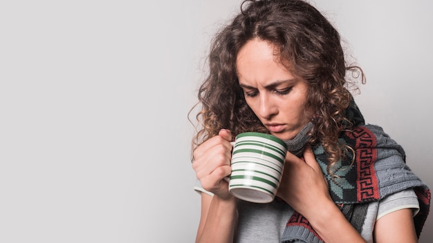 Free Photo sick woman looking in the coffee mug against white background