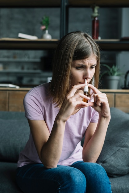 Free photo sick woman sniffing nasal spray