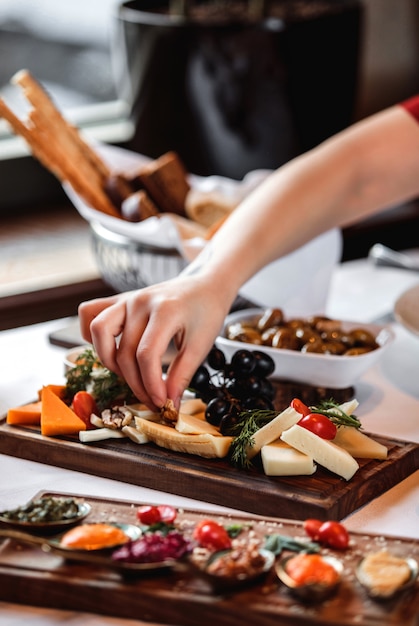 Free photo sidce view of various types of cheese with nuts grapes and honey on wooden platter