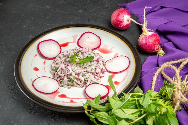 Free photo side close-up view an appetizing dish plate of radish and sauce herbs and purple tablecloth