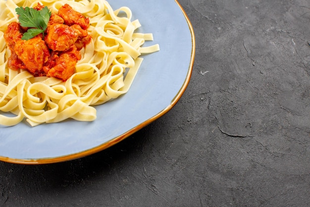 Free photo side close-up view appetizing food tasty pasta with meat and gravy in the blue plate on the dark table