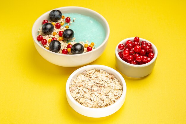 Side close-up view berries the appetizing colorful berries and oatmeal on the yellow table