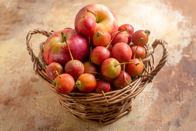 Side close-up view berries berries apples in the wooden basket on the cream table