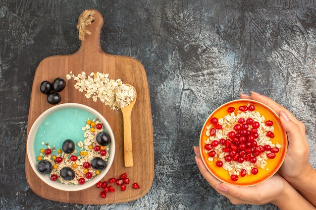 Side close-up view berries oatmeal berries on the board bowl of oatmeal pomegranate in the hands