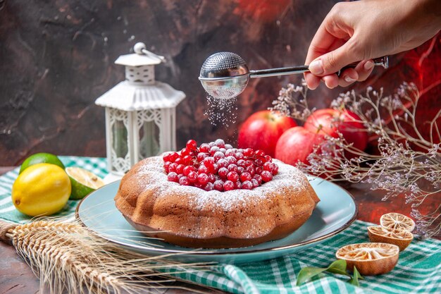 Side close-up view a cake an appetizing cake with berries lemons three apples spoon in the hand