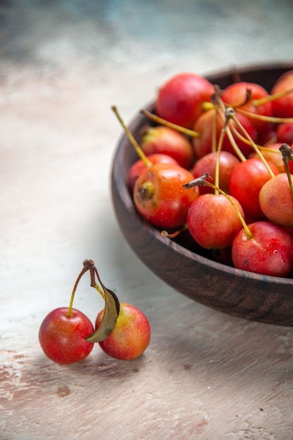 Side close-up view cherries cherries in the bowl next to the tree abranches