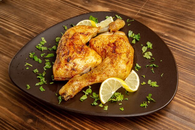 Side close-up view chicken and herbs plate of chicken legs with lemon and herbs on the dark background