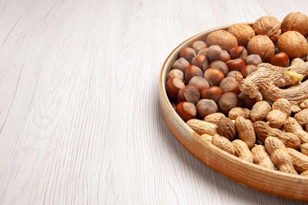 Side close-up view cinnamon sticks cinnamon sticks hazelnuts peanuts walnuts on the white table