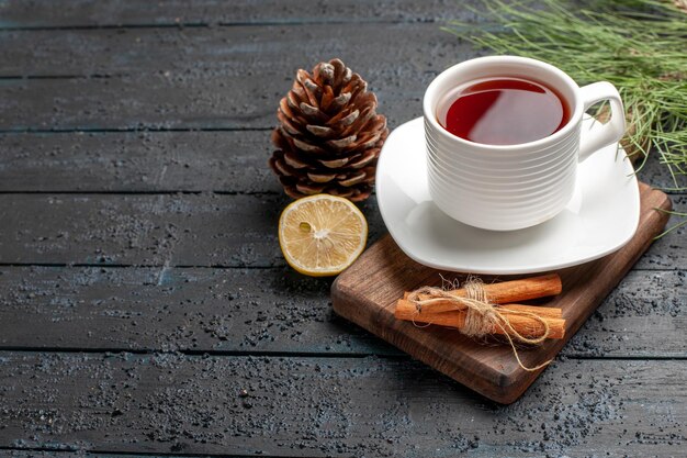 Side close-up view a cup of tea a cup of tea next to the cones lemon cinnamon sticks and Christmas tree branches