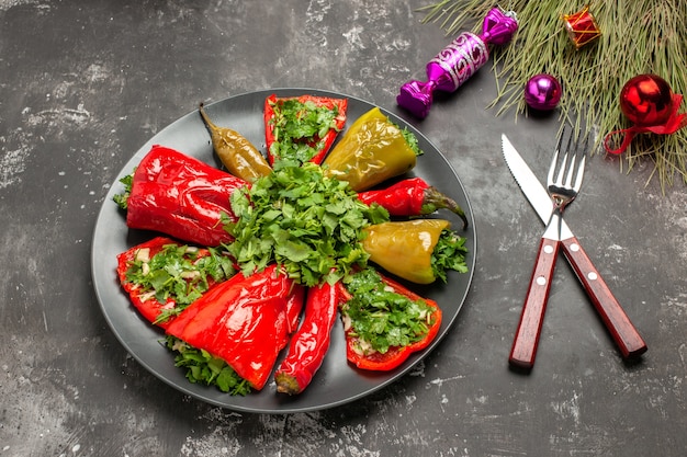 Side close-up view dish peppers with herbs knife fork candies Christmas toys